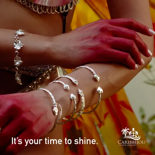 Caribbijou campaign image: silver bangles and a floral bracelet worn on a woman's arms, captioned "It's your time to shine." beside the Caribbijou Island Jewelry logo.
